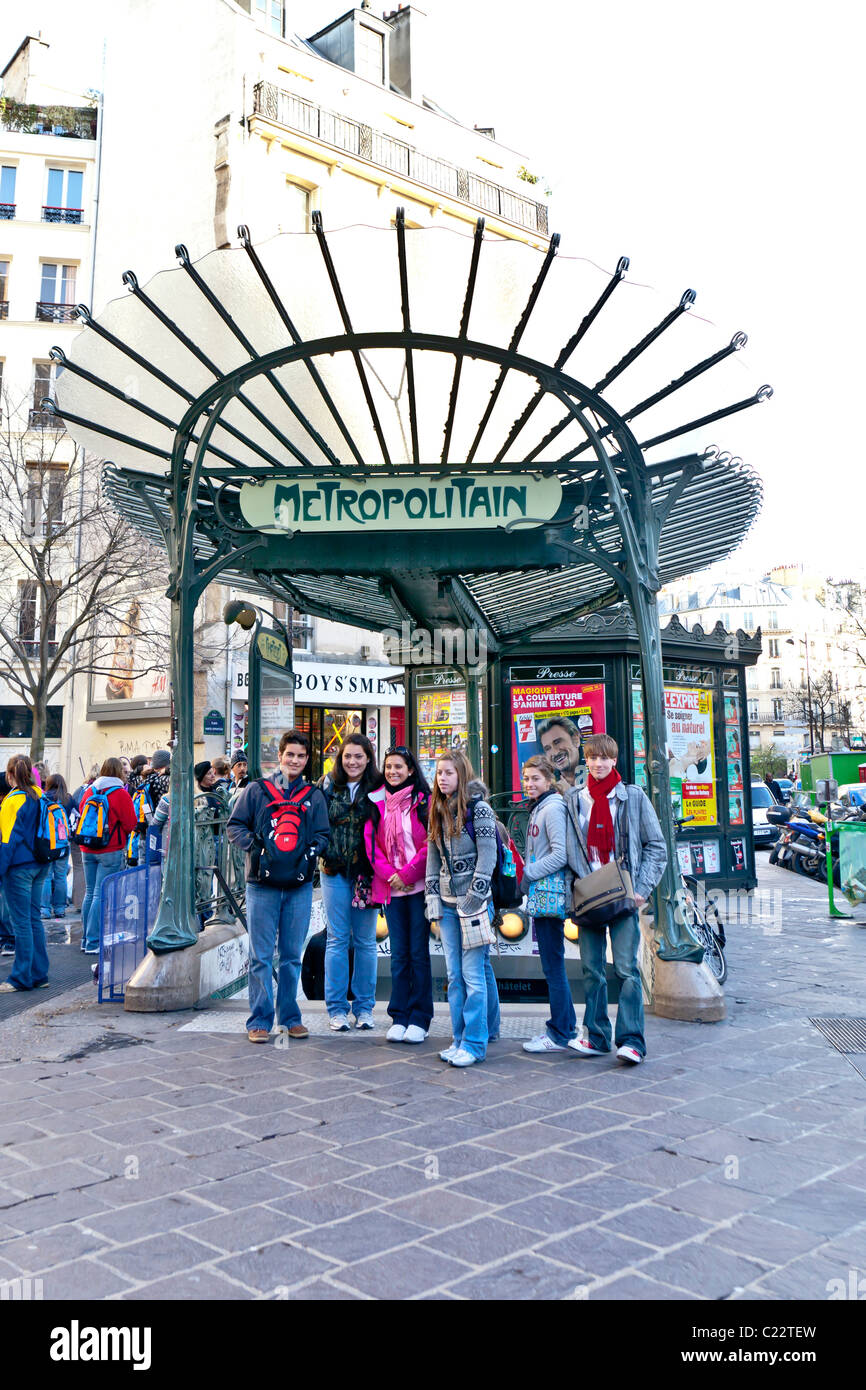 Un gruppo di giovani posano per una foto davanti a un art-nouveau metropolitana Metro segno; Parigi Francia. Charles Lupica Foto Stock