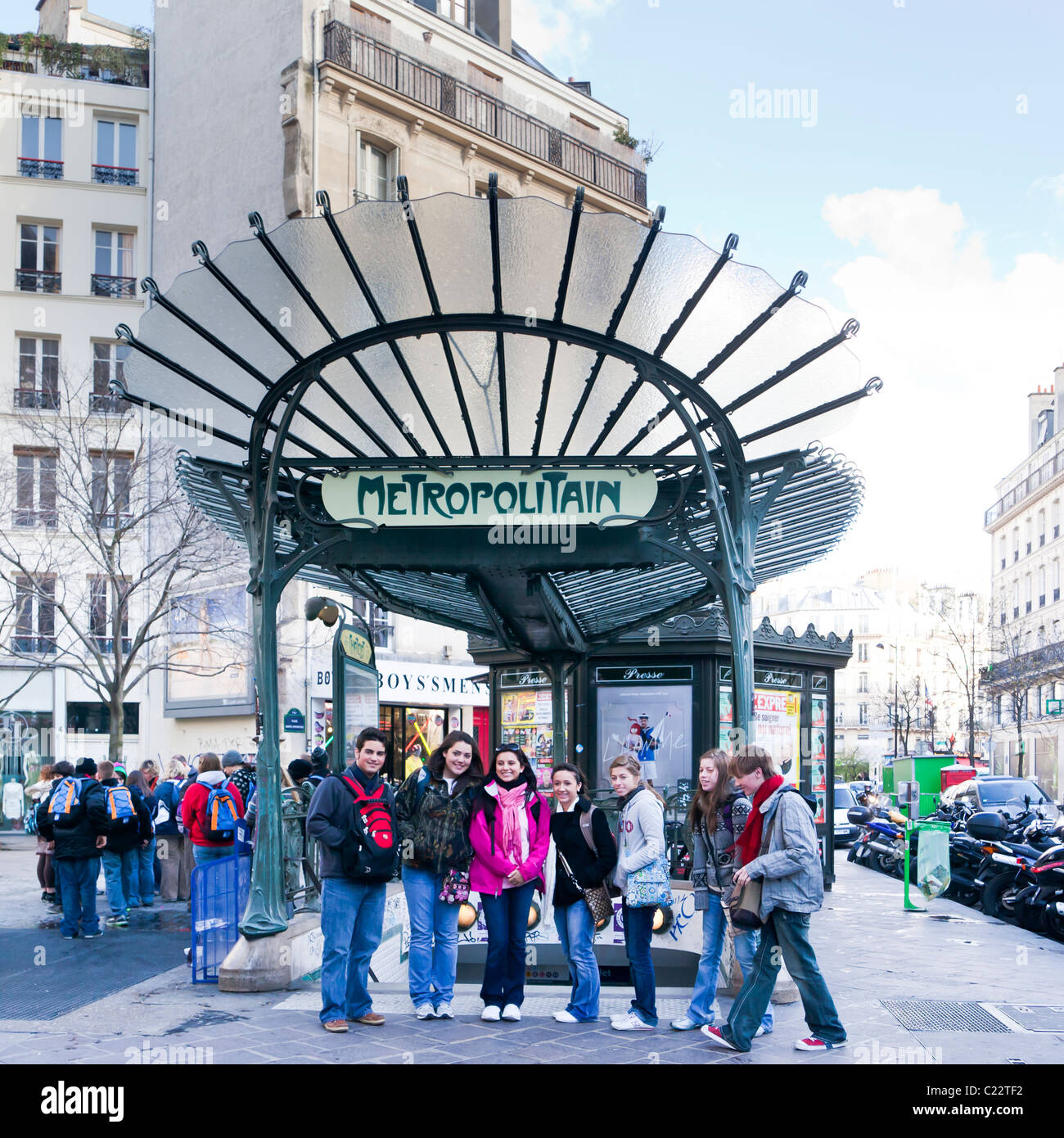 Un gruppo di giovani posano per una foto davanti a un art-nouveau metropolitana Metro segno; Parigi Francia. Charles Lupica Foto Stock