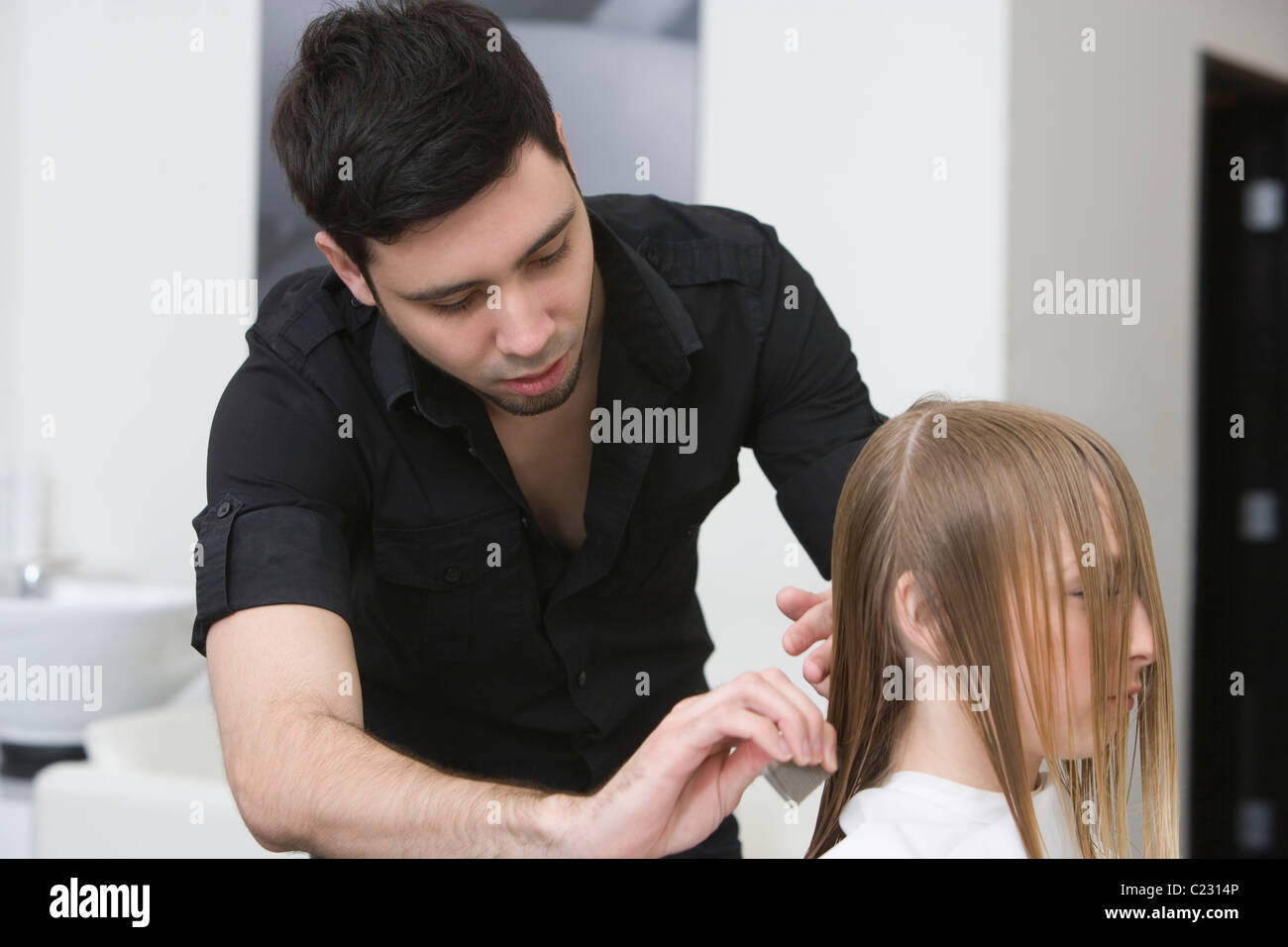 L'uomo il taglio e la pettinatura di una giovane donna capelli in parrucchieri Foto Stock