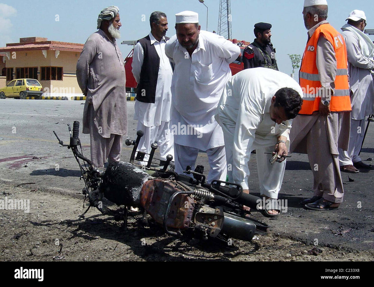 Pianura-panno di funzionari di polizia ispezionare un motociclo danneggiato che era stato distrutto in esplosione dopo l esplosione di Swabi mercoledì Foto Stock