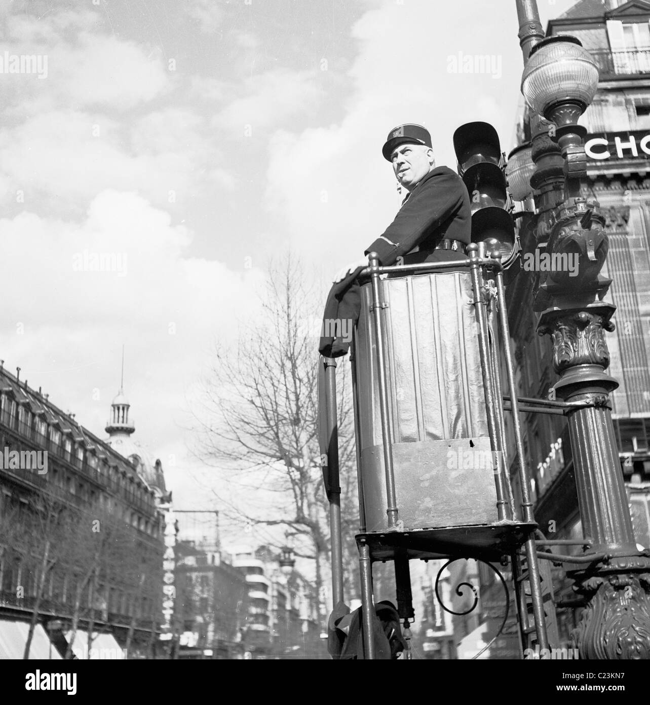 1950s, un poliziotto francese in uniforme con fischio in bocca, in alto posto di controllo su un lampione in Avenue de l'Opera, Parigi. Francia. Foto Stock