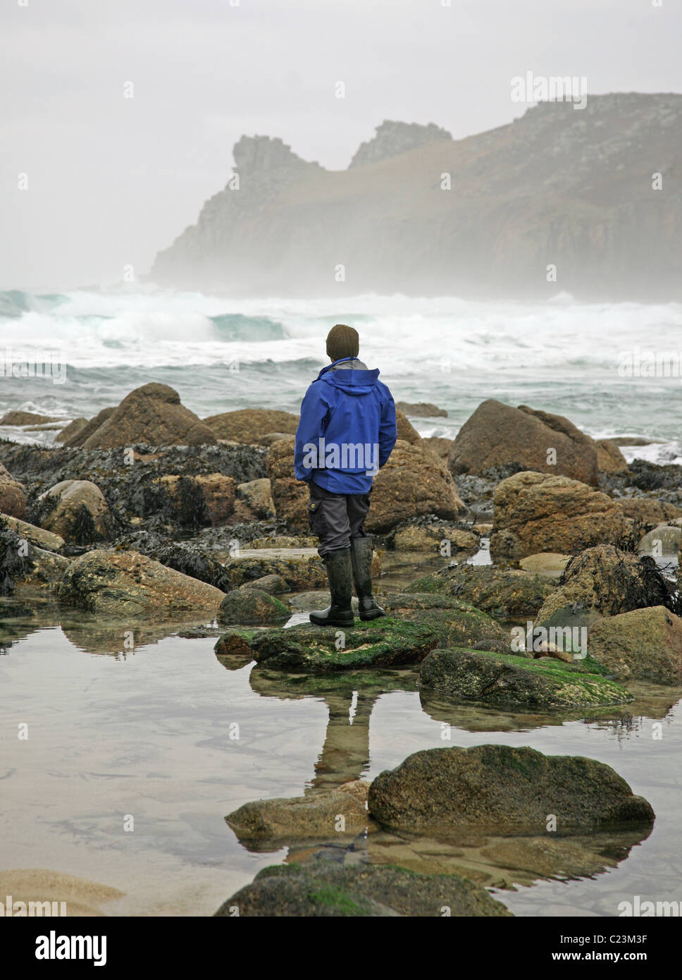 Un uomo si affaccia al mare e rocce a Nanjizal o Mill Bay un Cornish cove, Cornwall, West Country, Inghilterra, inverno 2010 Foto Stock