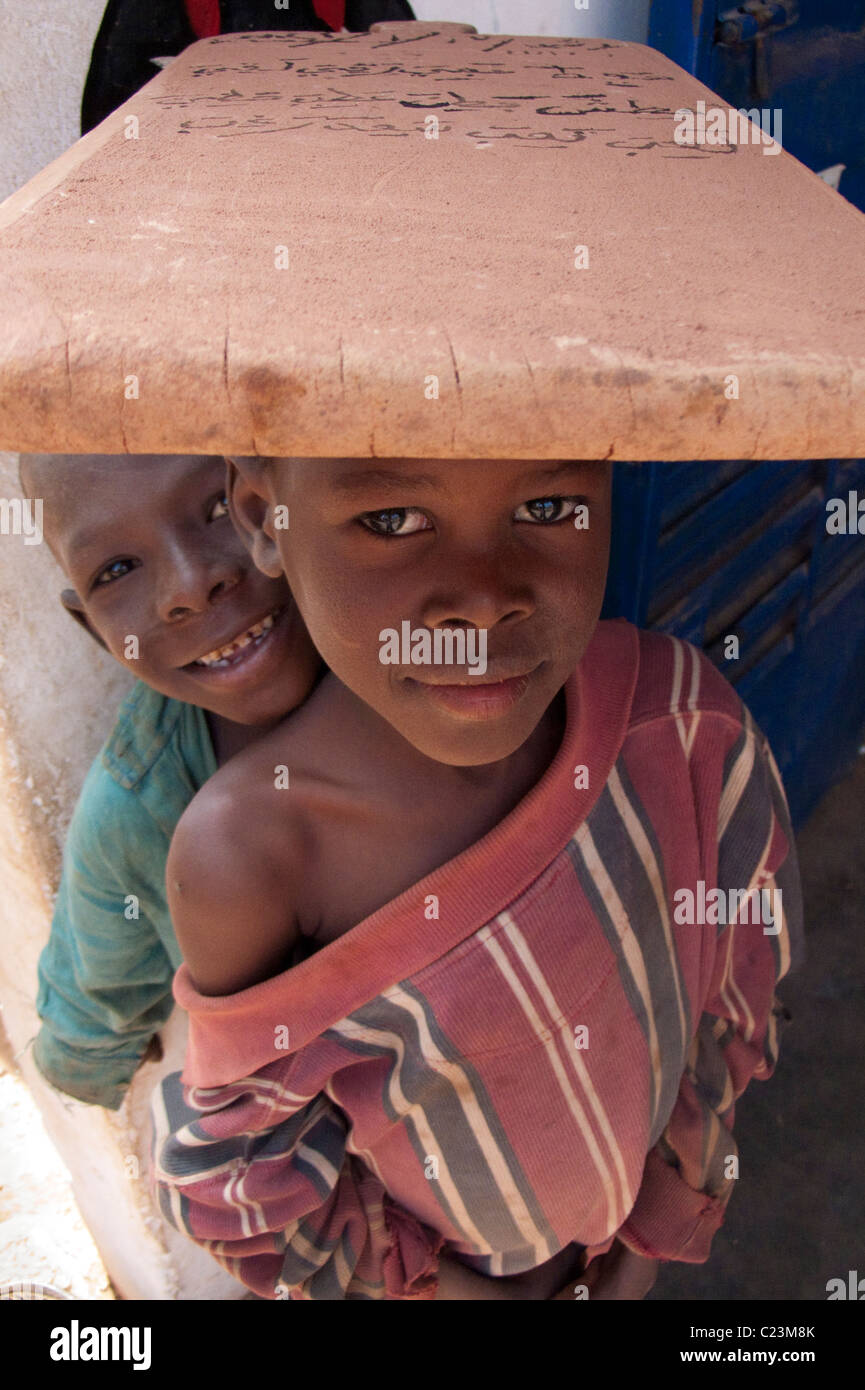 Scolaro che trasportano tavoletta da scrittura sulla sua testa nel trimestre Kibédoué di Bobo Dioulasso Foto Stock
