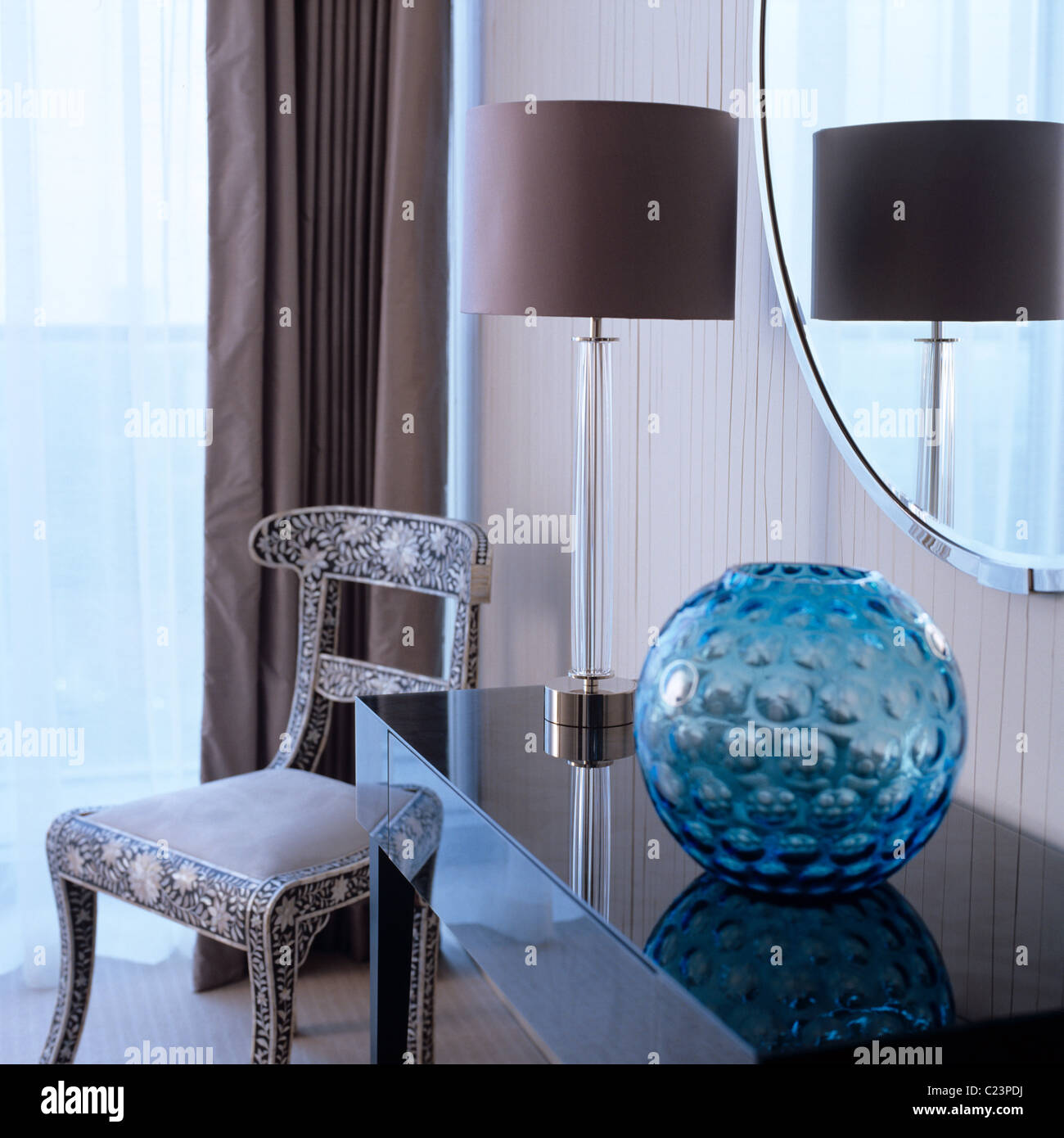 Anni Cinquanta la ciotola di vetro e il supporto della lampada sul lucido tavolo console in camera con intarsi di sedia indiano. Foto Stock