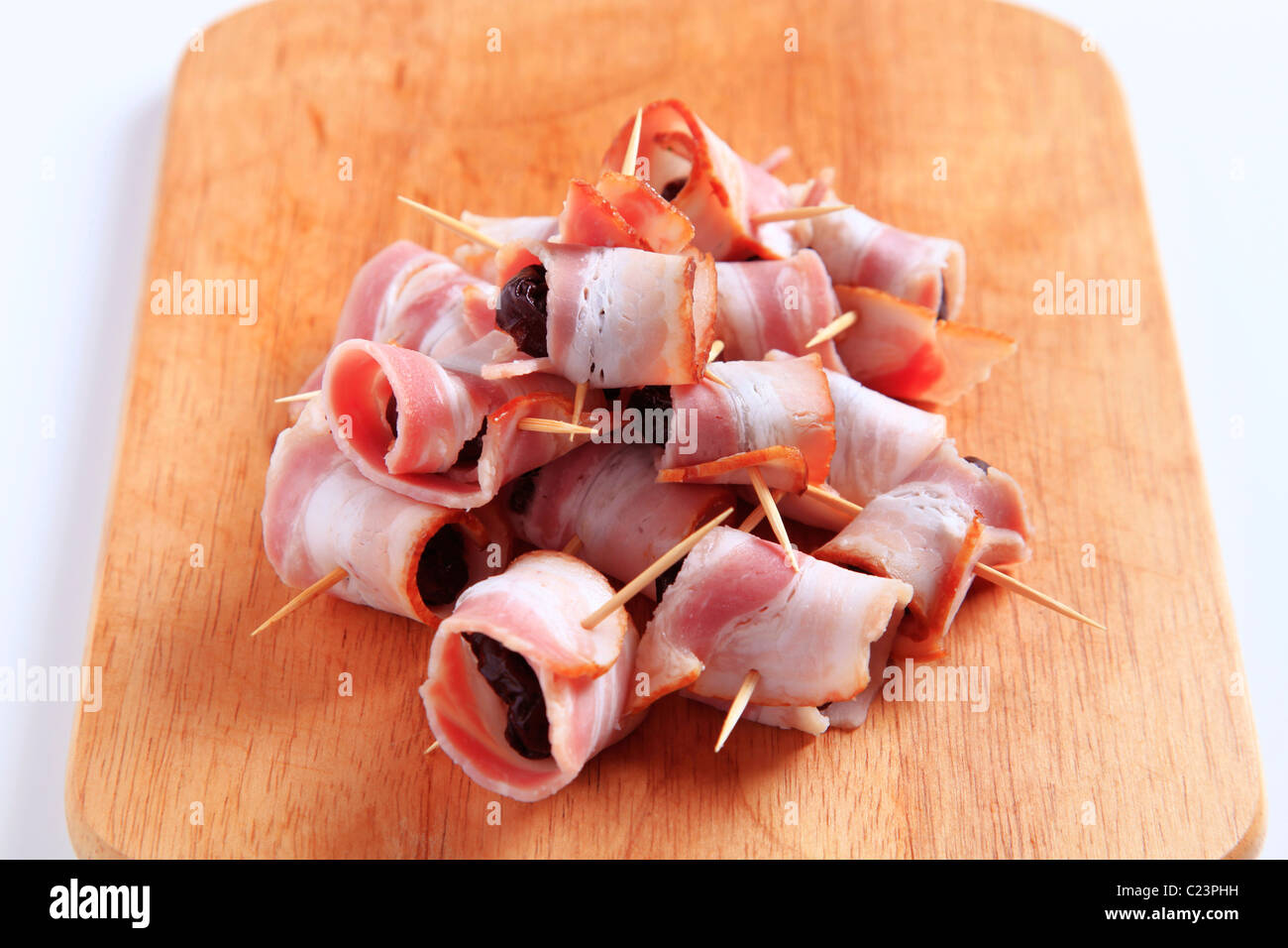 Pancetta avvolto prugne su un tagliere Foto Stock