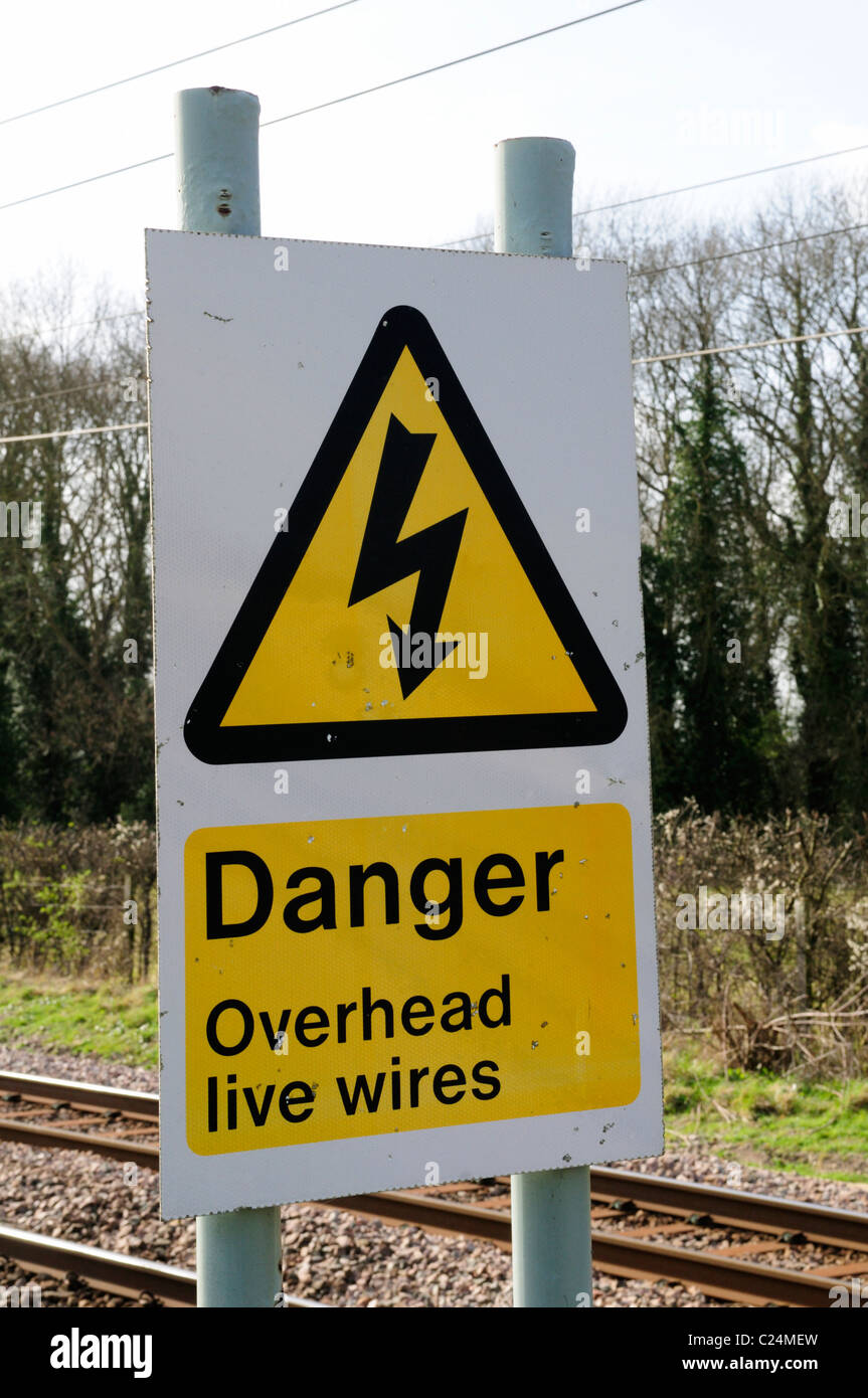 Pericolo cavi aerei sotto tensione segnale di avvertimento a fianco della linea ferroviaria, Harston, Cambridgeshire, England, Regno Unito Foto Stock
