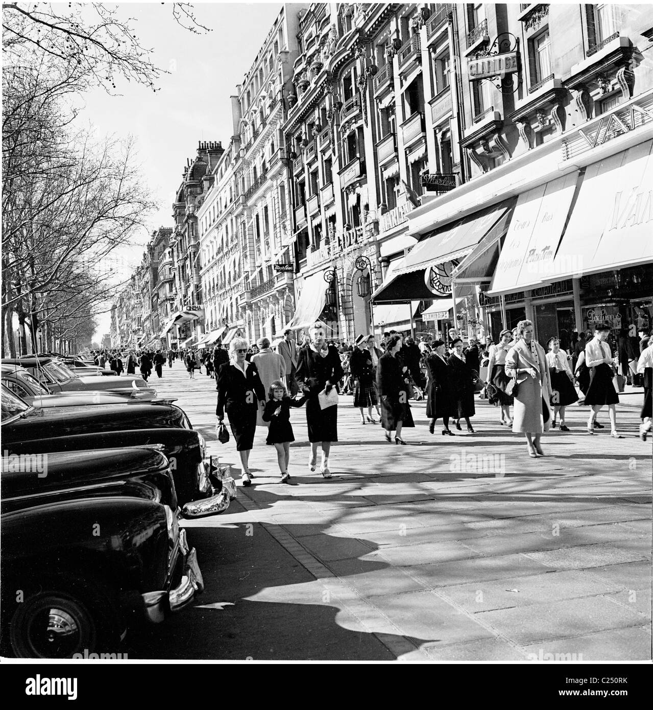 Parigi, Francia, anni '50. I parigini camminano lungo il marciapiede sull'elegante strada fiancheggiata da negozi, gli Champs-Elysees, una delle strade più famose del mondo. Foto Stock
