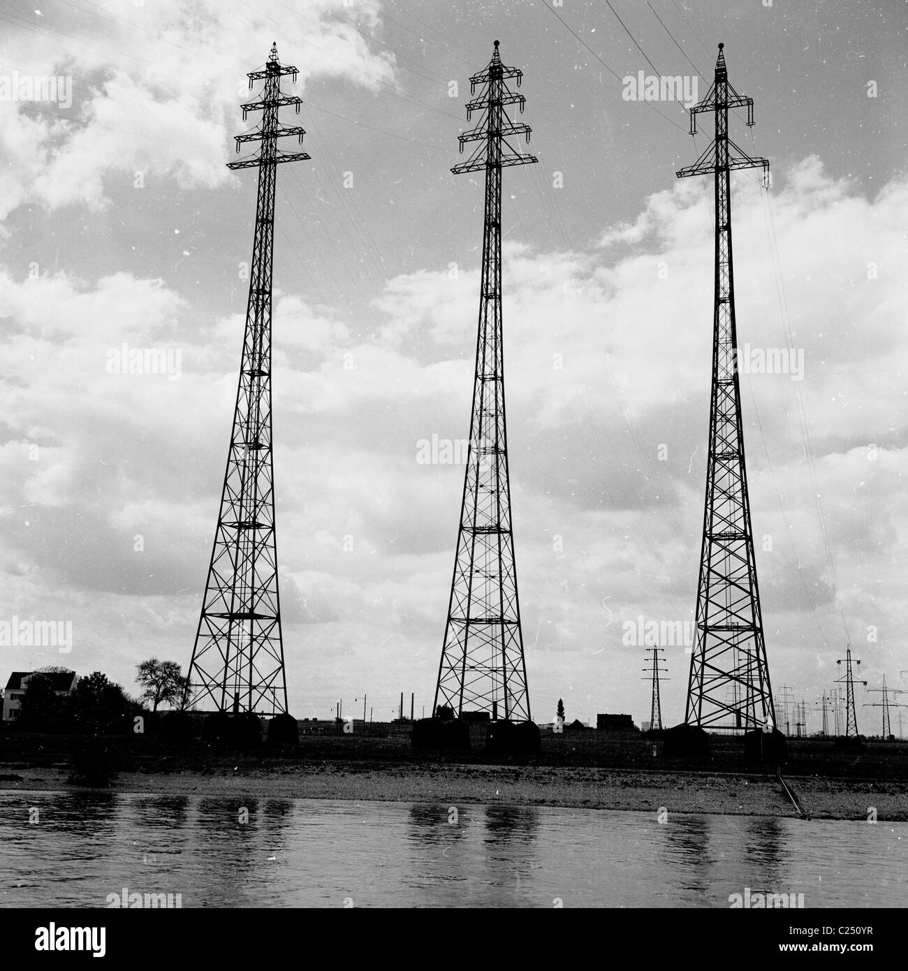 Degli anni Cinquanta, Germania. Tre electricty tralicci sedersi accanto al fiume Reno vicino a Leverkusen. Foto Stock