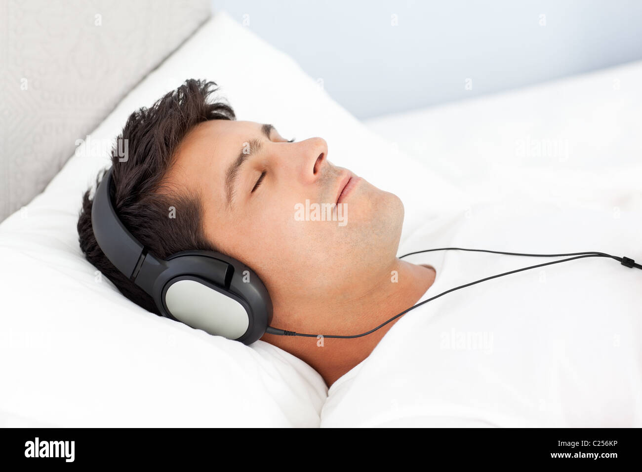 Uomo sereno ascoltando musica sdraiato sul suo letto Foto Stock