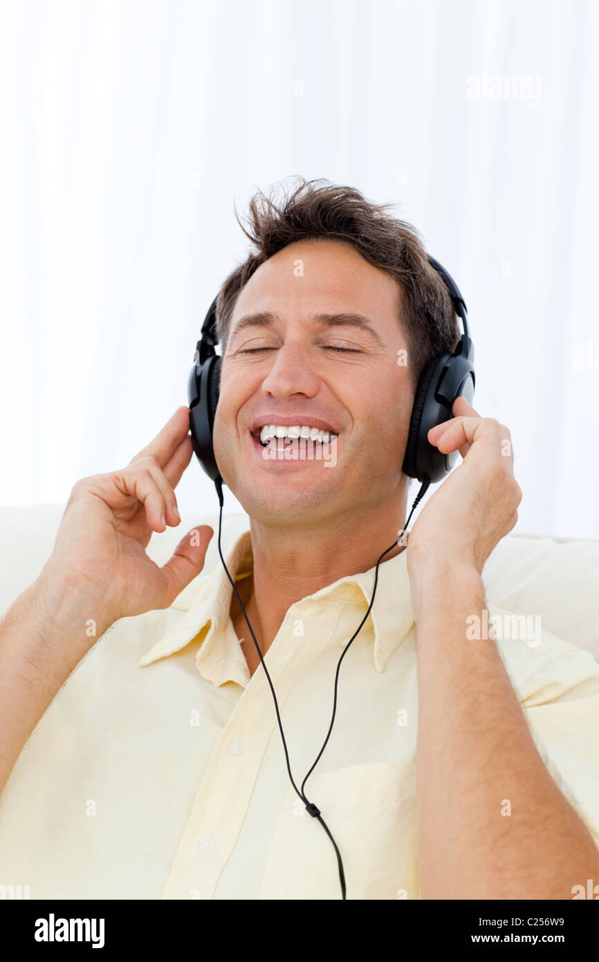 Uomo Felice di cantare mentre ascolti la musica sul divano Foto Stock