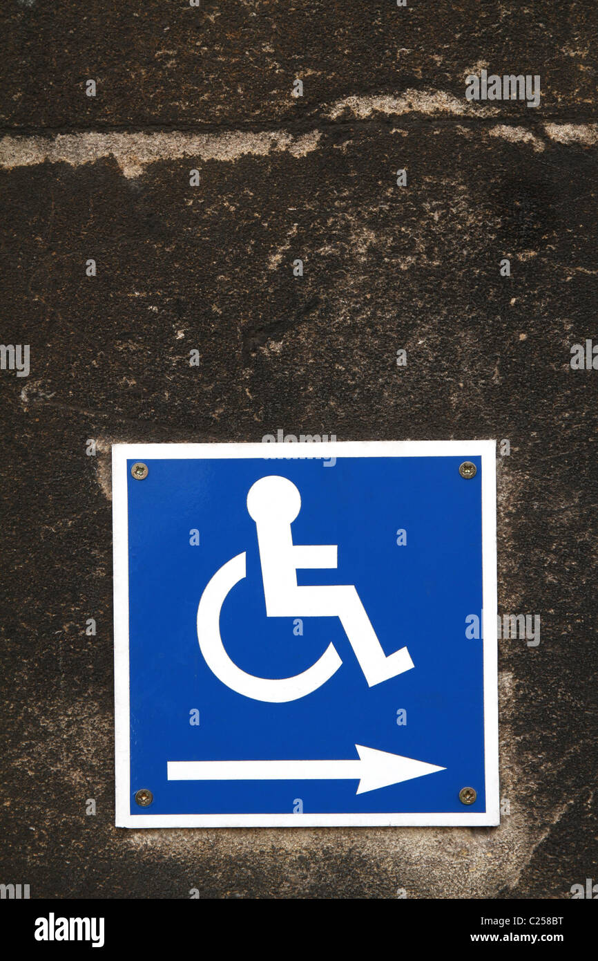 Accesso per disabili segno distintivo su un muro di pietra Foto Stock