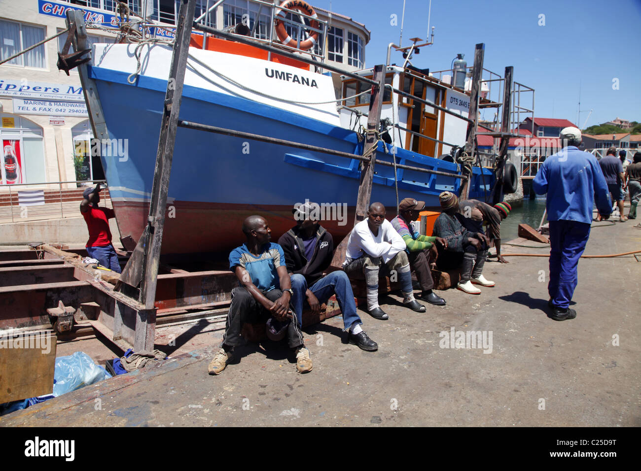 Colorati di nero lavoratori sedersi vicino a barca da pesca di ST. Francesco Harbour Eastern Cape SUD AFRICA 26 Gennaio 2011 Foto Stock