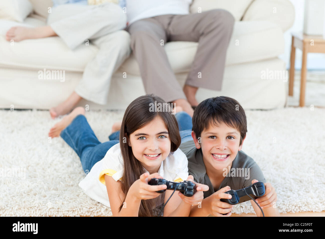 I bambini giocare ai videogiochi mentre i genitori sono in conversazione Foto Stock