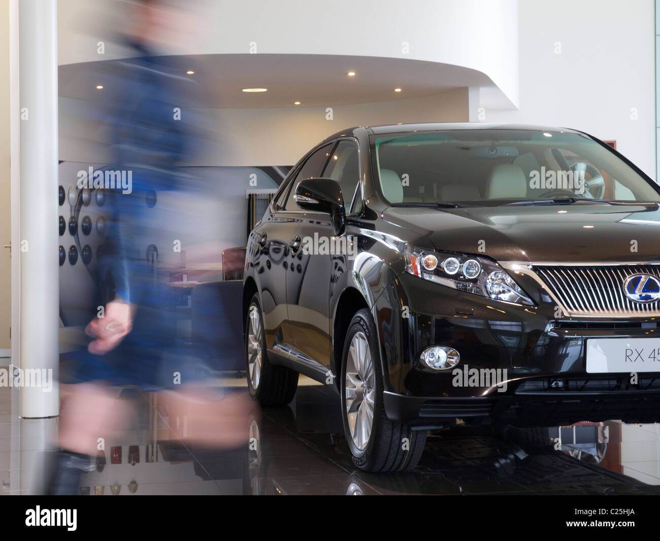 Lexus RX450h SUV ibrido in showroom con donna sfocata passato a piedi in vestito blu Foto Stock