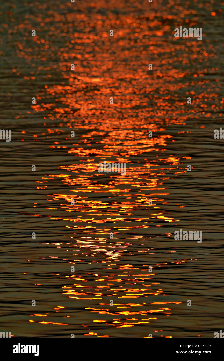 Regolazione del sole riflessa nella superficie di un fiume che scorre Foto Stock