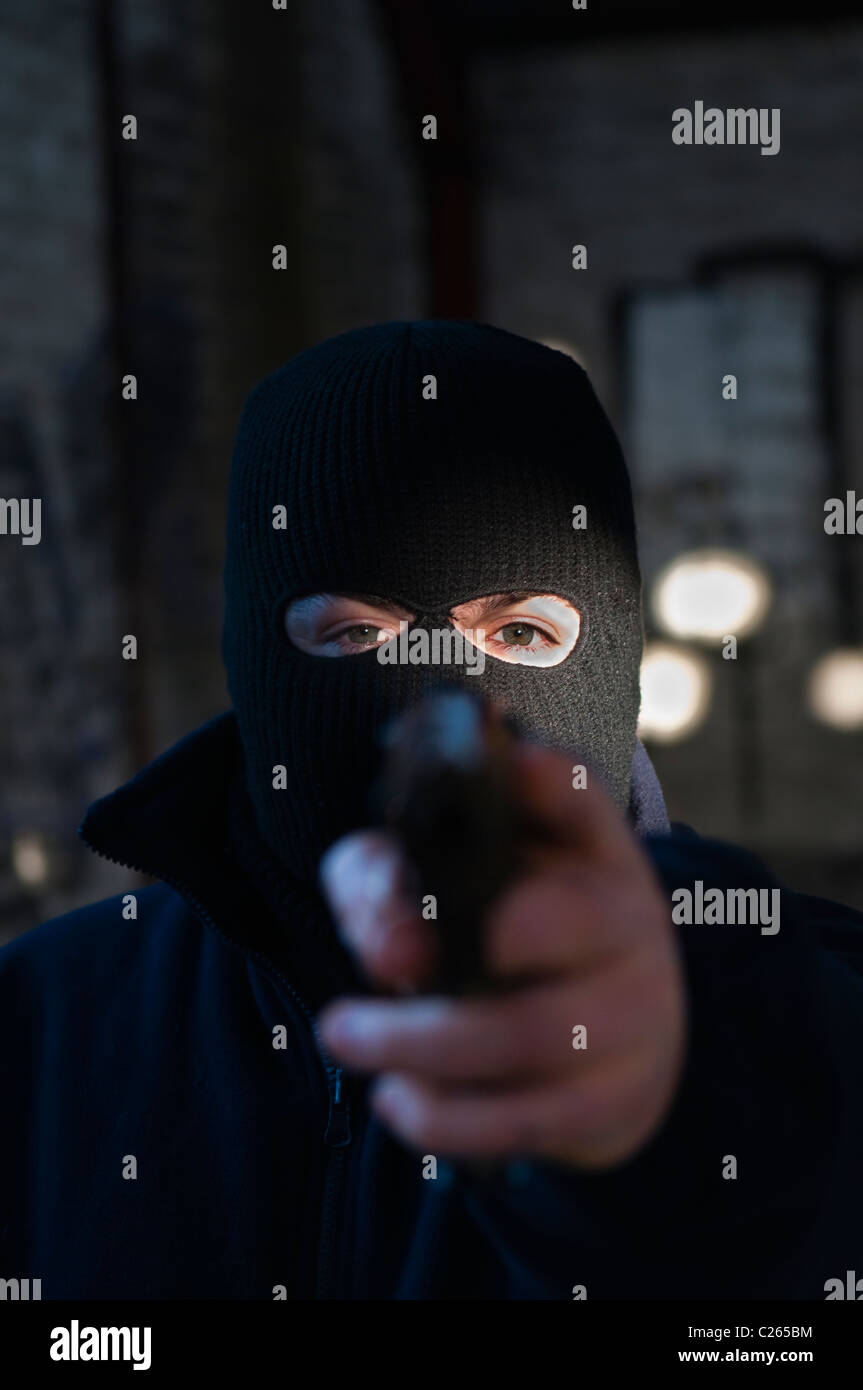 L'uomo/terrorista che indossa un passamontagna nero, puntando una pistola al visualizzatore Foto Stock