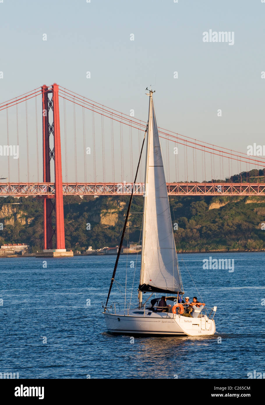 Uno yacht della vela sul fiume Tago si avvicina al Ponte 25 de Abril ponte di sospensione, nei pressi di Lisbona. Foto Stock