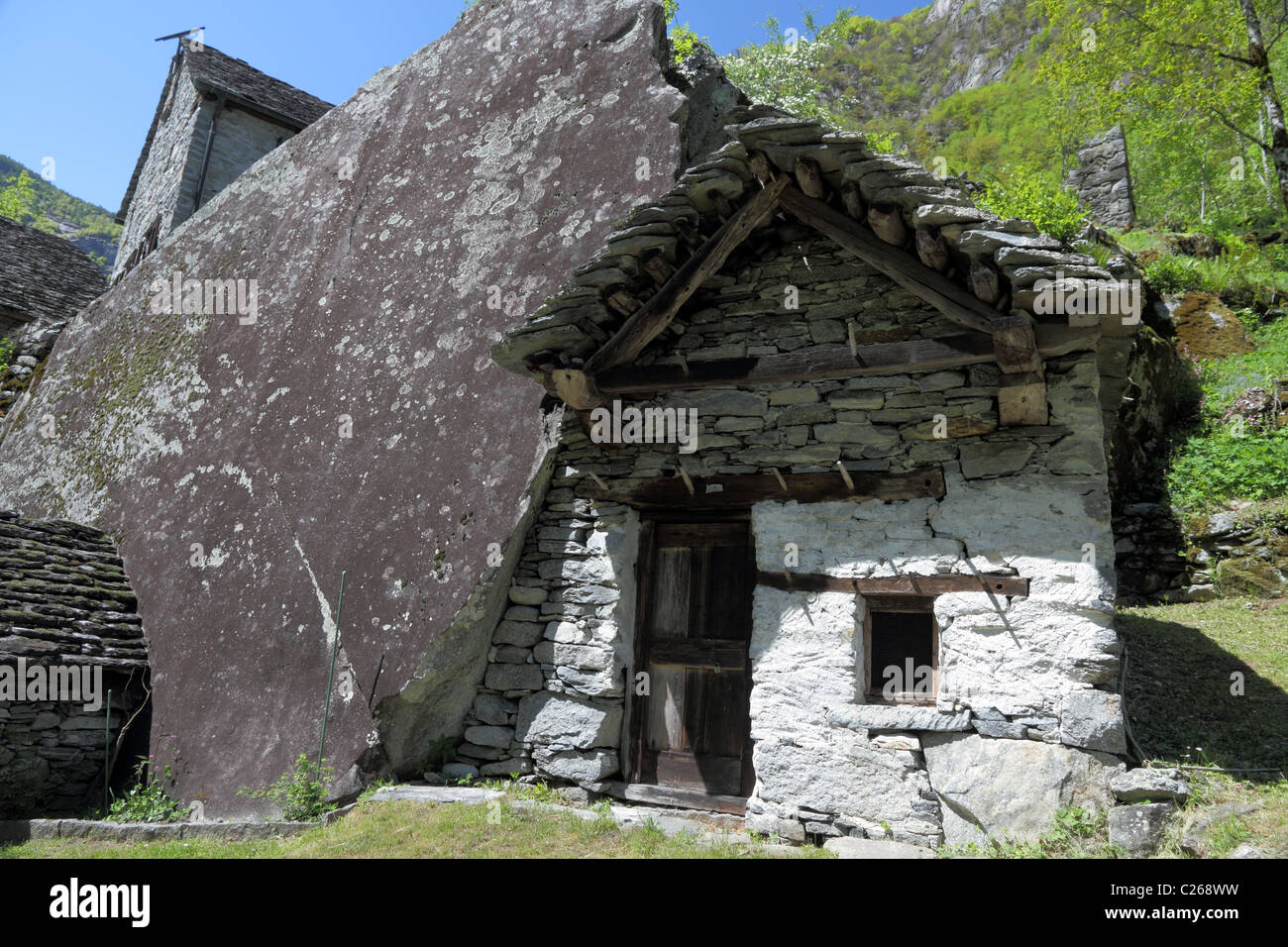 Vecchie case incorporante una enorme roccia messo insieme da pietra grezza in Valle Bavona la più selvaggia t di tutti Ticino, Svizzera Foto Stock