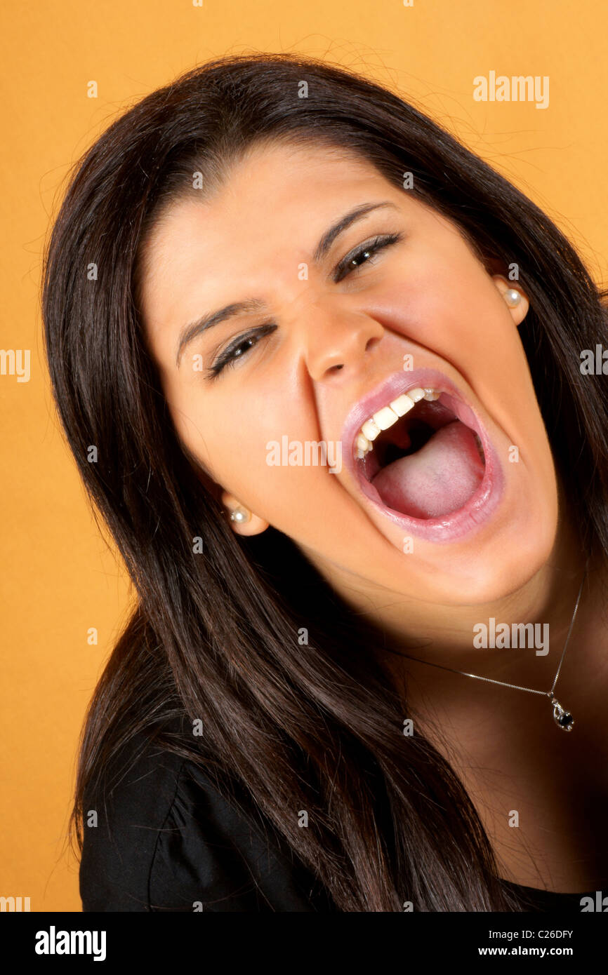 Ritratto di un urlando 18 anni giovane donna su uno sfondo arancione Foto Stock