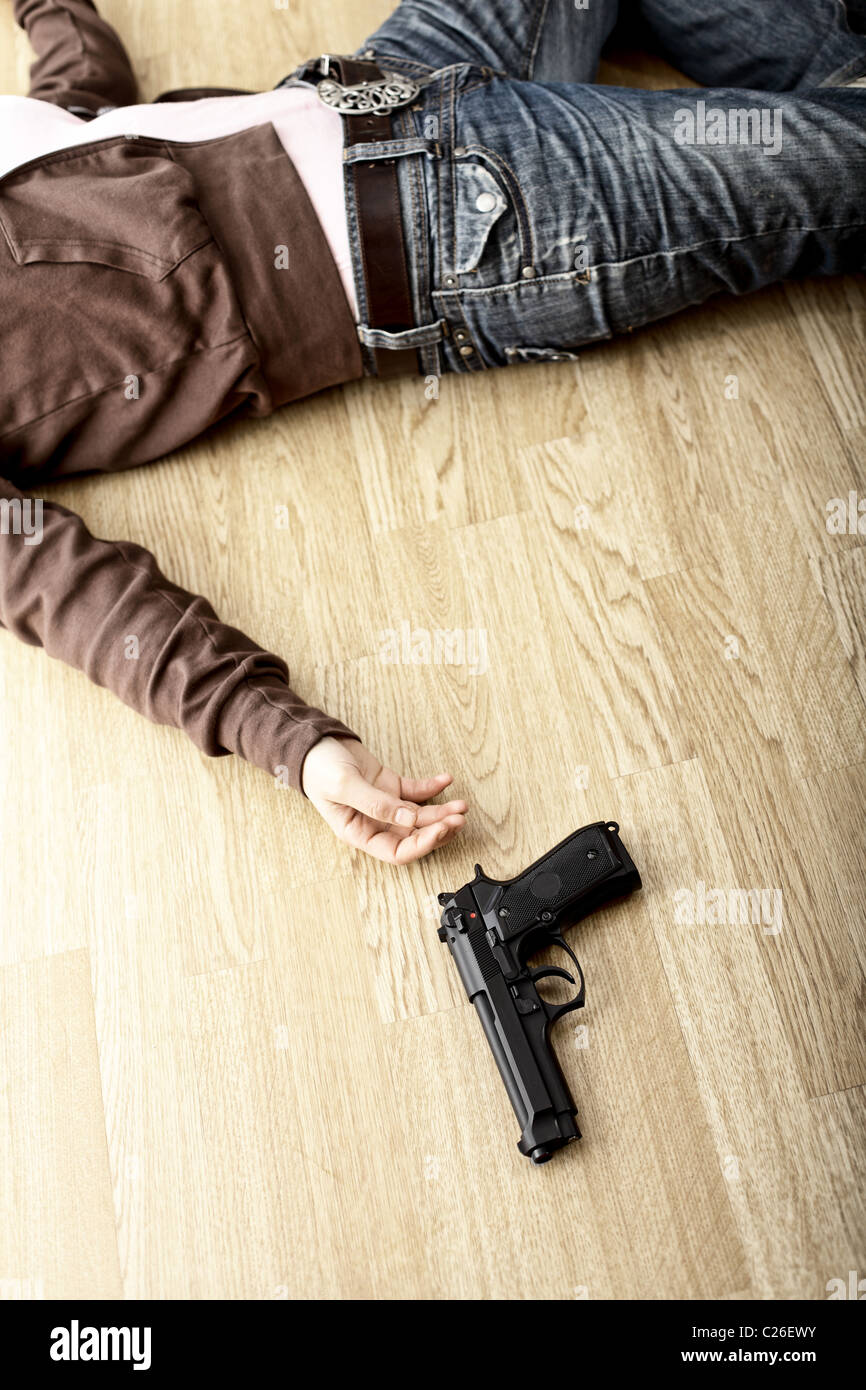 Scena del crimine, corpo morto sul pavimento e pistola Foto Stock