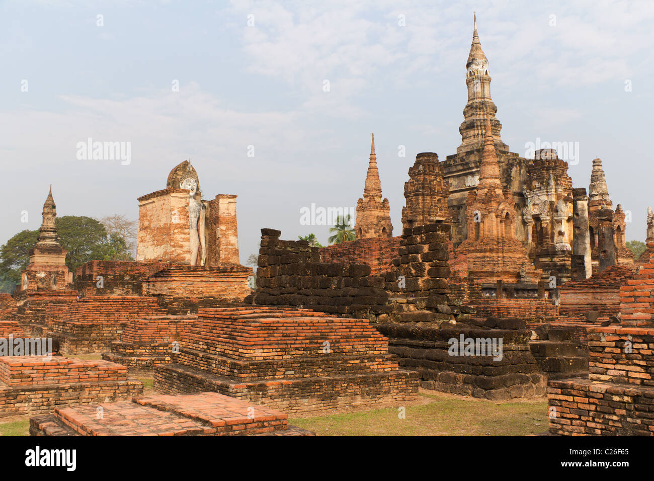 Statua di Budda e i resti di un tempio di Wat Mahathat presso il sito Patrimonio Mondiale dell'UNESCO di Sukothai in Thailandia Foto Stock