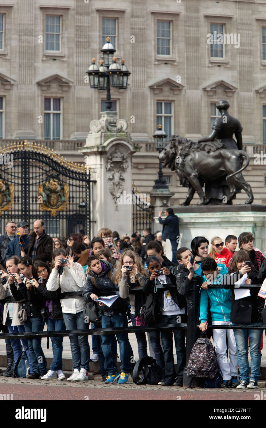 La scuola dei bambini a guardare il cambio della guardia al di fuori del Palazzo di Buckingham Foto Stock