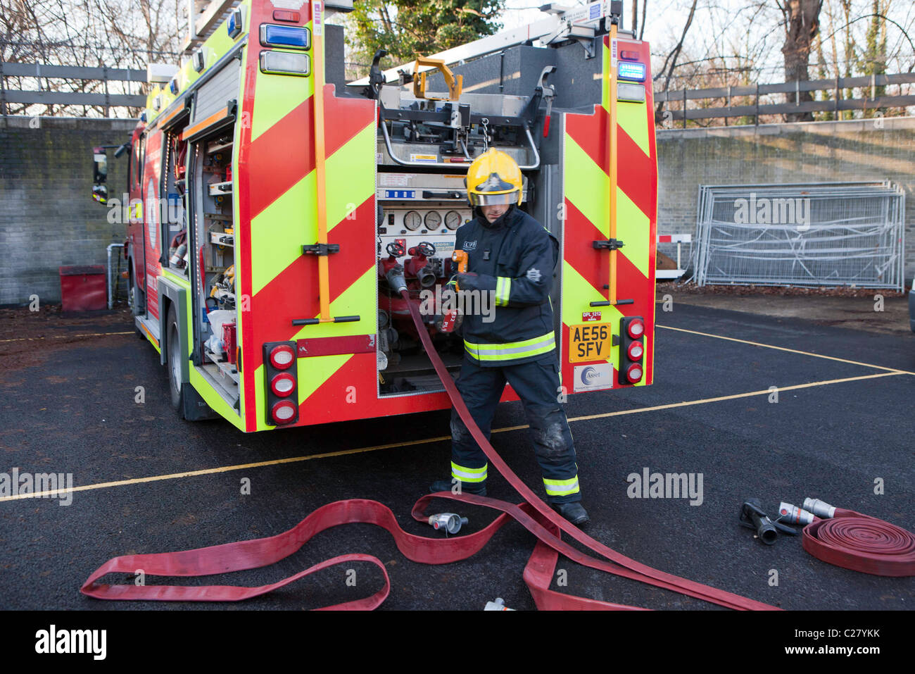 Londra Vigili del Fuoco, stazione la sessione di formazione. Un incendio fighter consente di collegare i tubi flessibili al motore fire. Foto Stock