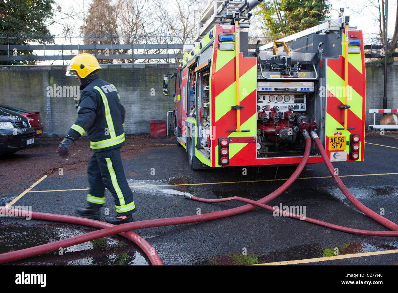 Londra Vigili del Fuoco, stazione la sessione di formazione. Un incendio fighter consente di collegare i tubi flessibili al motore fire. Foto Stock