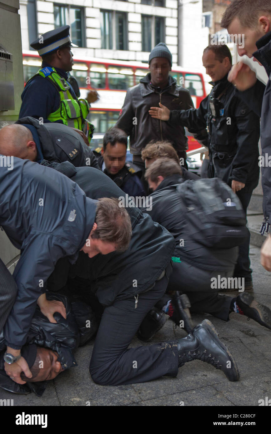 Un giovane maschio nero viene arrestato. Ci sono voluti dieci ufficiali da varie forze per superare questo uomo e di arrestarlo in modo sicuro. Londra. Foto Stock