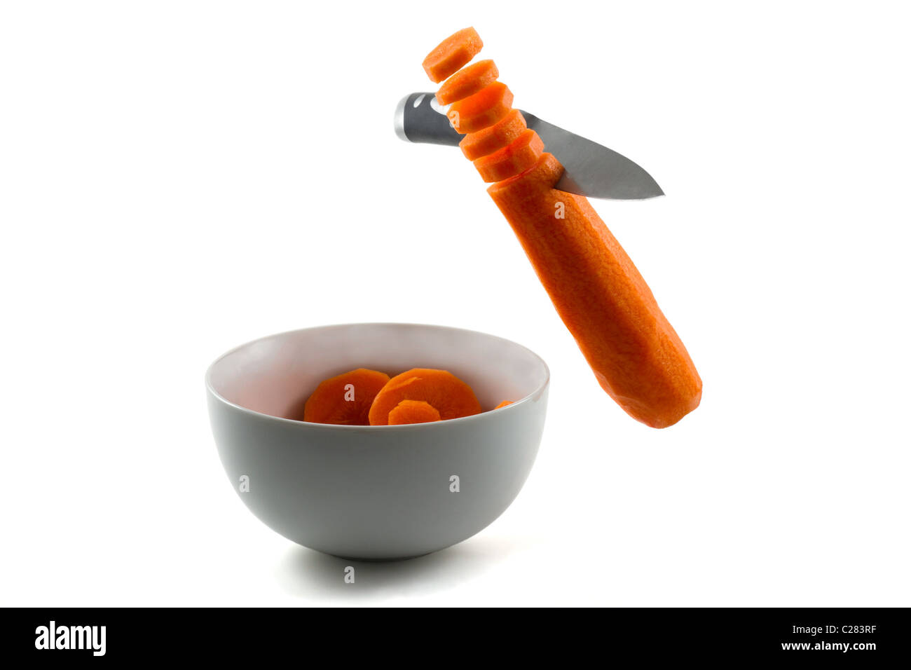 Un coltello tritare le carote in aria e nella vaschetta di colore bianco Foto Stock
