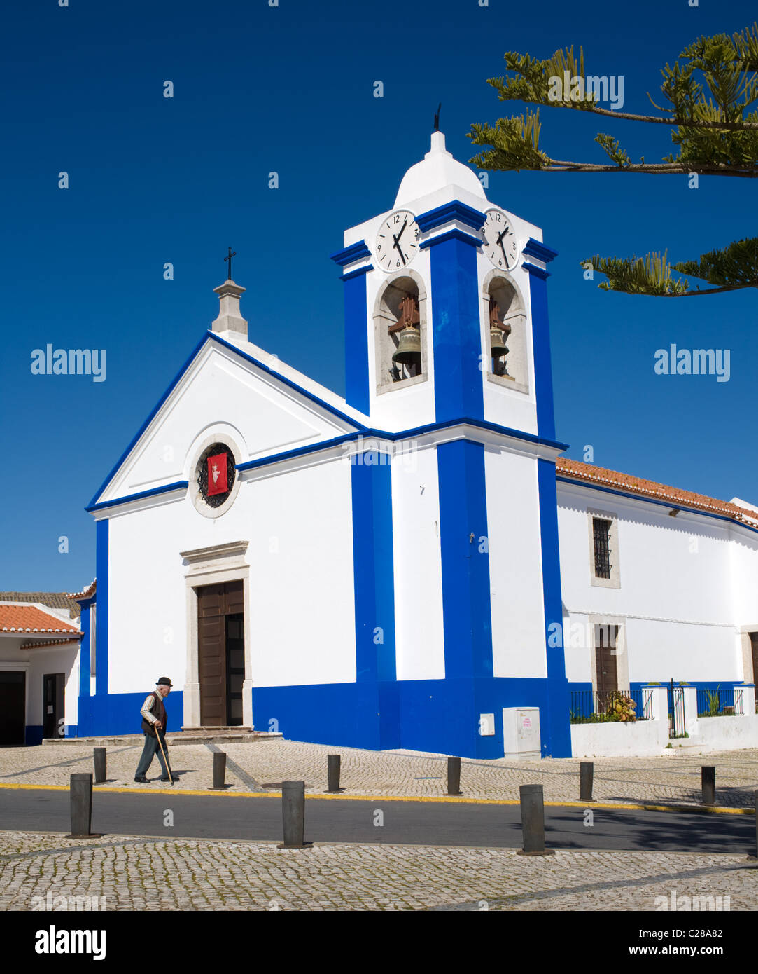 Uomo che cammina dalla chiesa nel Alentejo villaggio di São Teotónio, Portogallo Foto Stock