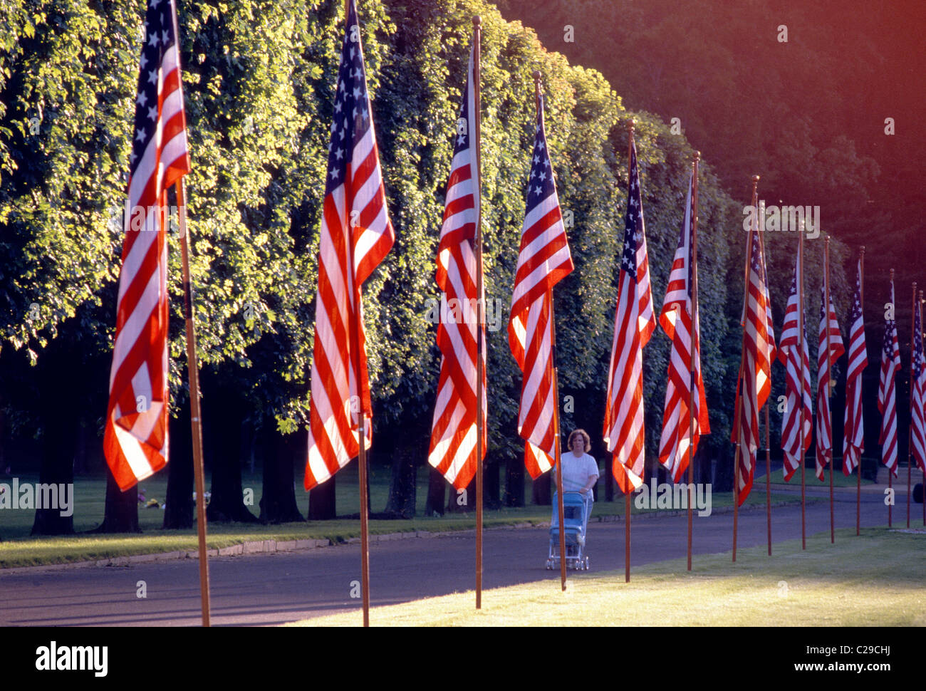Donna che cammina il suo bambino carrello lungo la vecchia gloria, bandiera degli Stati Uniti d'America, volare sul quarto di luglio Foto Stock