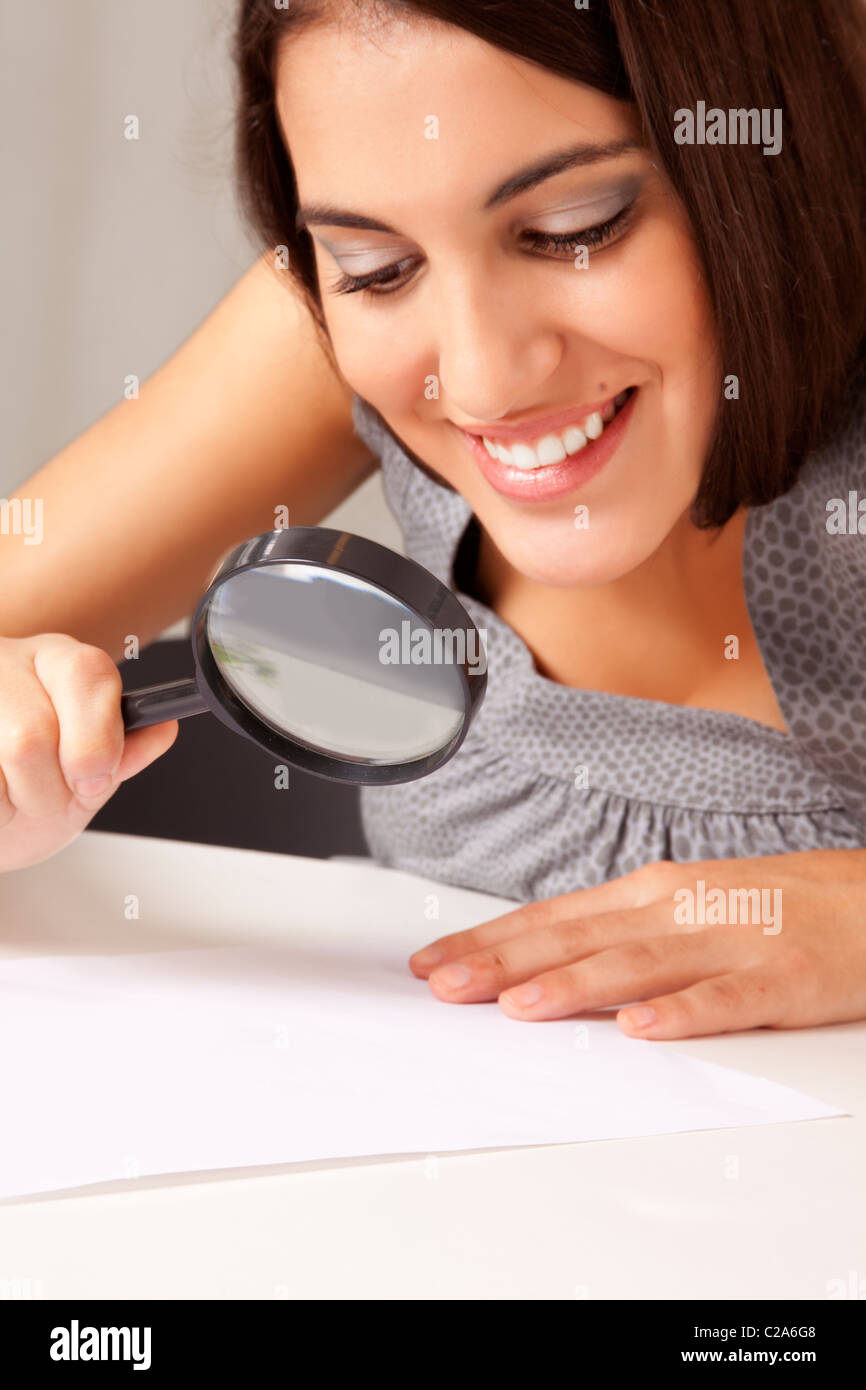 Un prety brunette donna guardando una carta con una lente di ingrandimento Foto Stock
