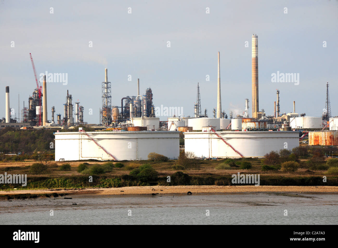 A coastal raffineria di petrolio con i serbatoi di stoccaggio e comignoli fumanti Foto Stock