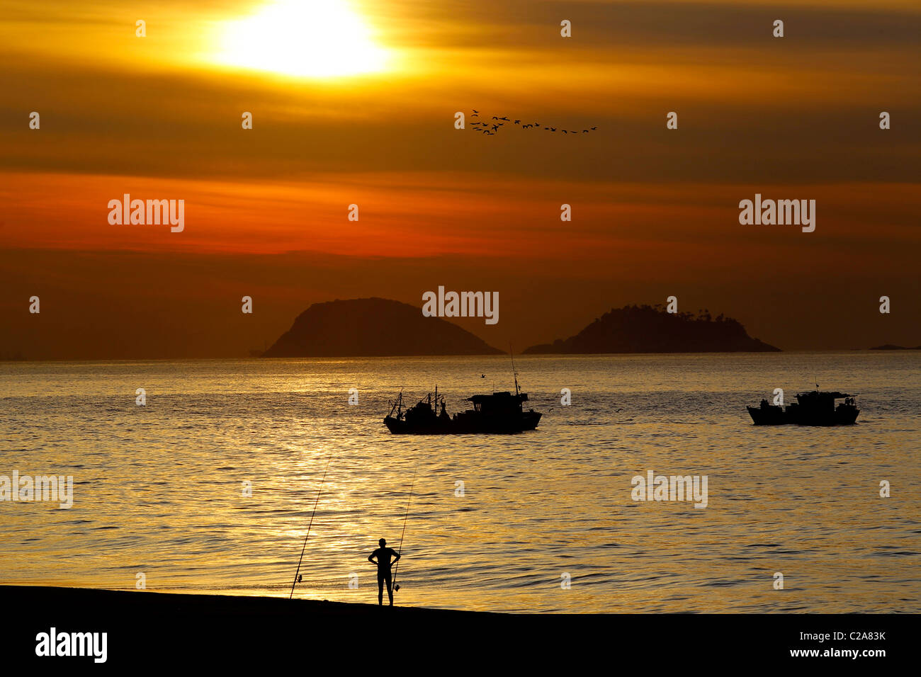 Pescatore in la spiaggia di Barra da Tijuca all alba con barche di pescatori in background. Foto Stock