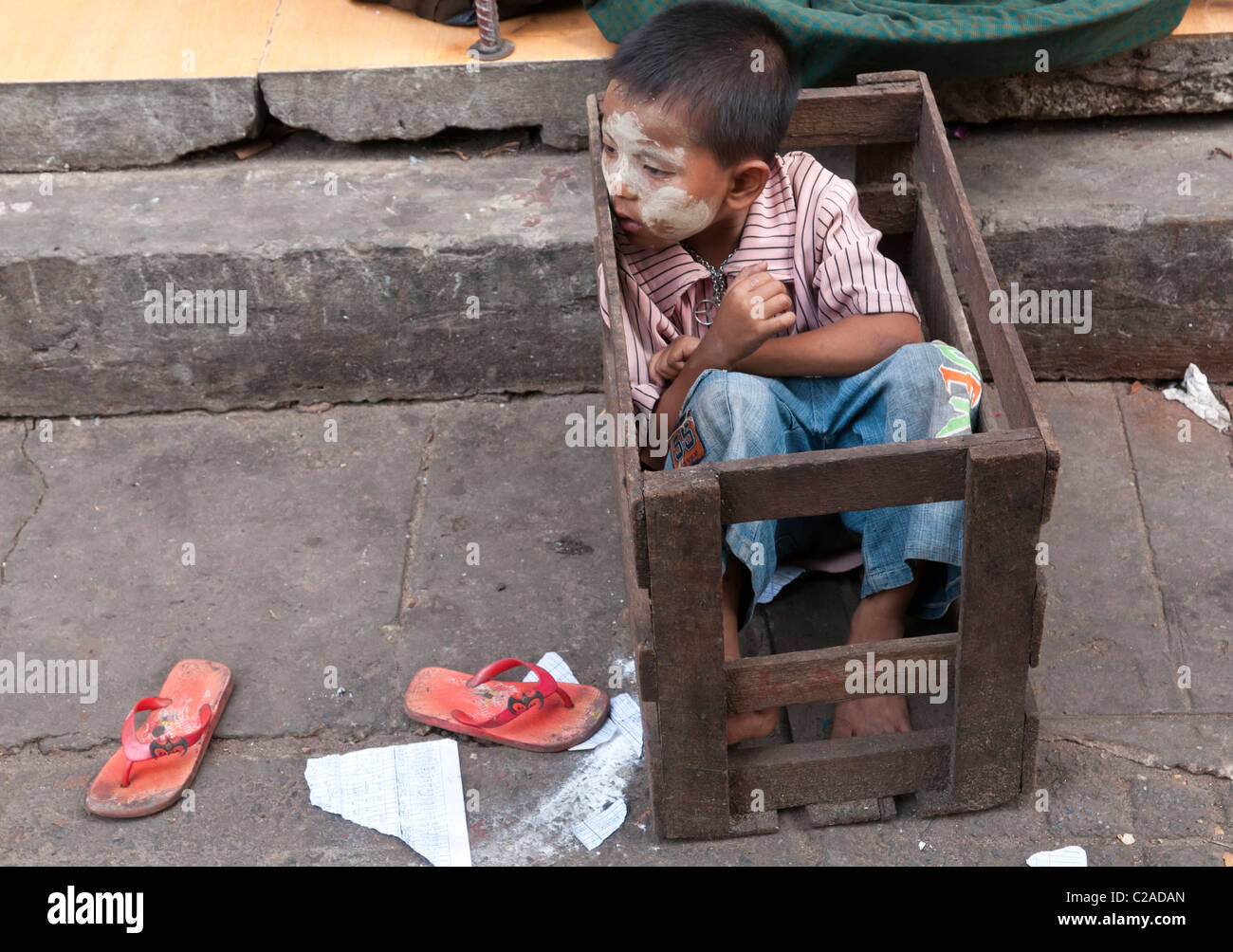 Ragazzo seduto in una scatola di legno. Yangon. Myanmar Foto Stock