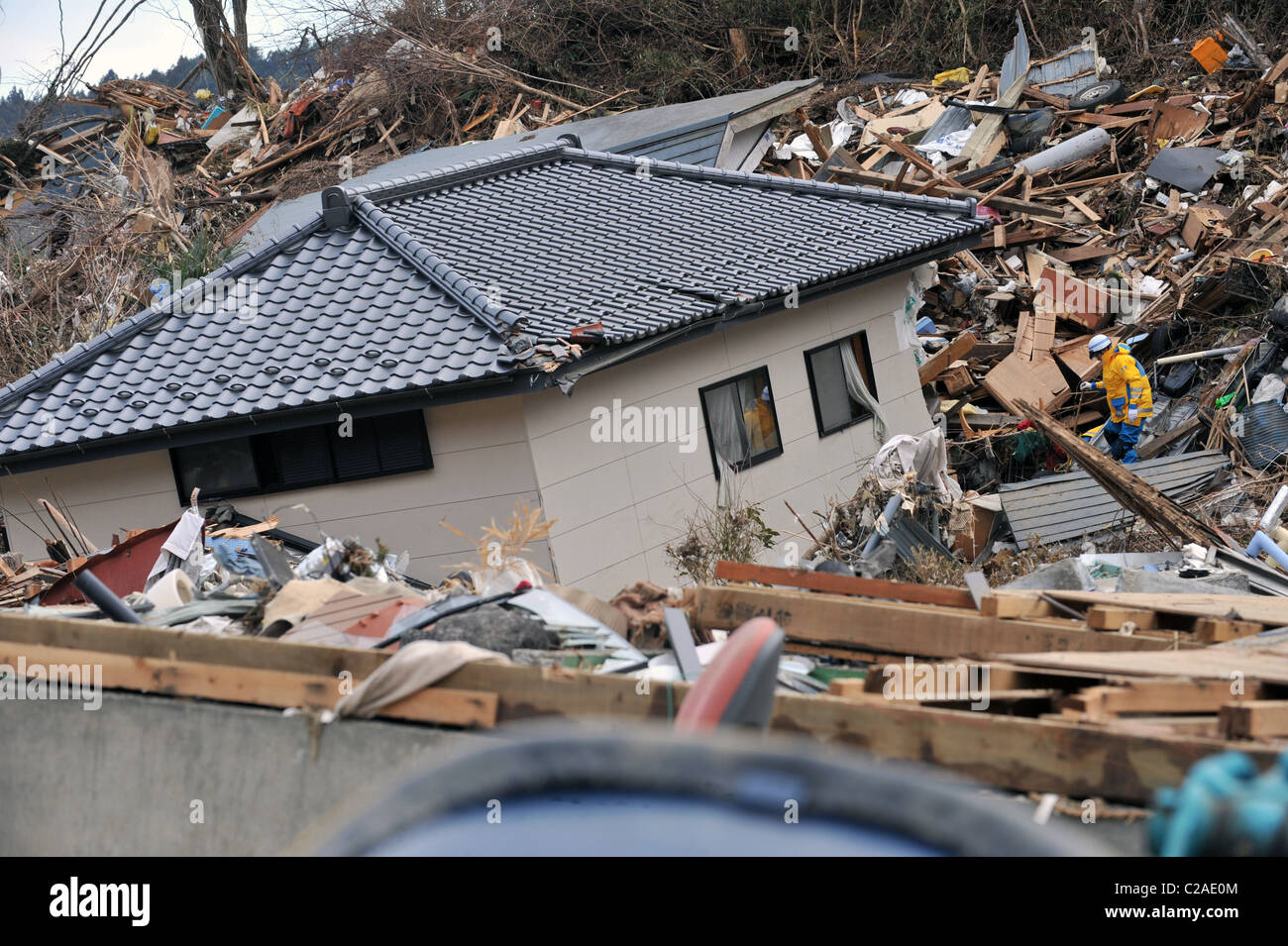 La ricerca in giapponese e delle squadre di soccorso alla ricerca di superstiti dopo migliaia di abitazioni sono state distrutte dopo un 9.0 Mw terremoto Foto Stock