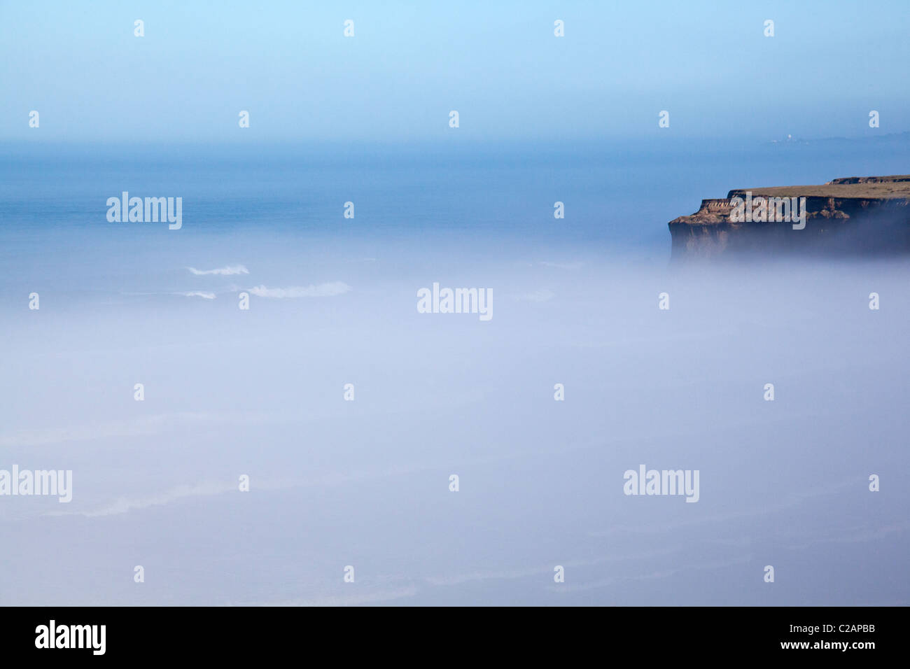 Una fetta di litorale frastagliato bluff sporge al di sopra della nebbia blanketing, avvolgente, la California Coast Highway 1. Foto Stock