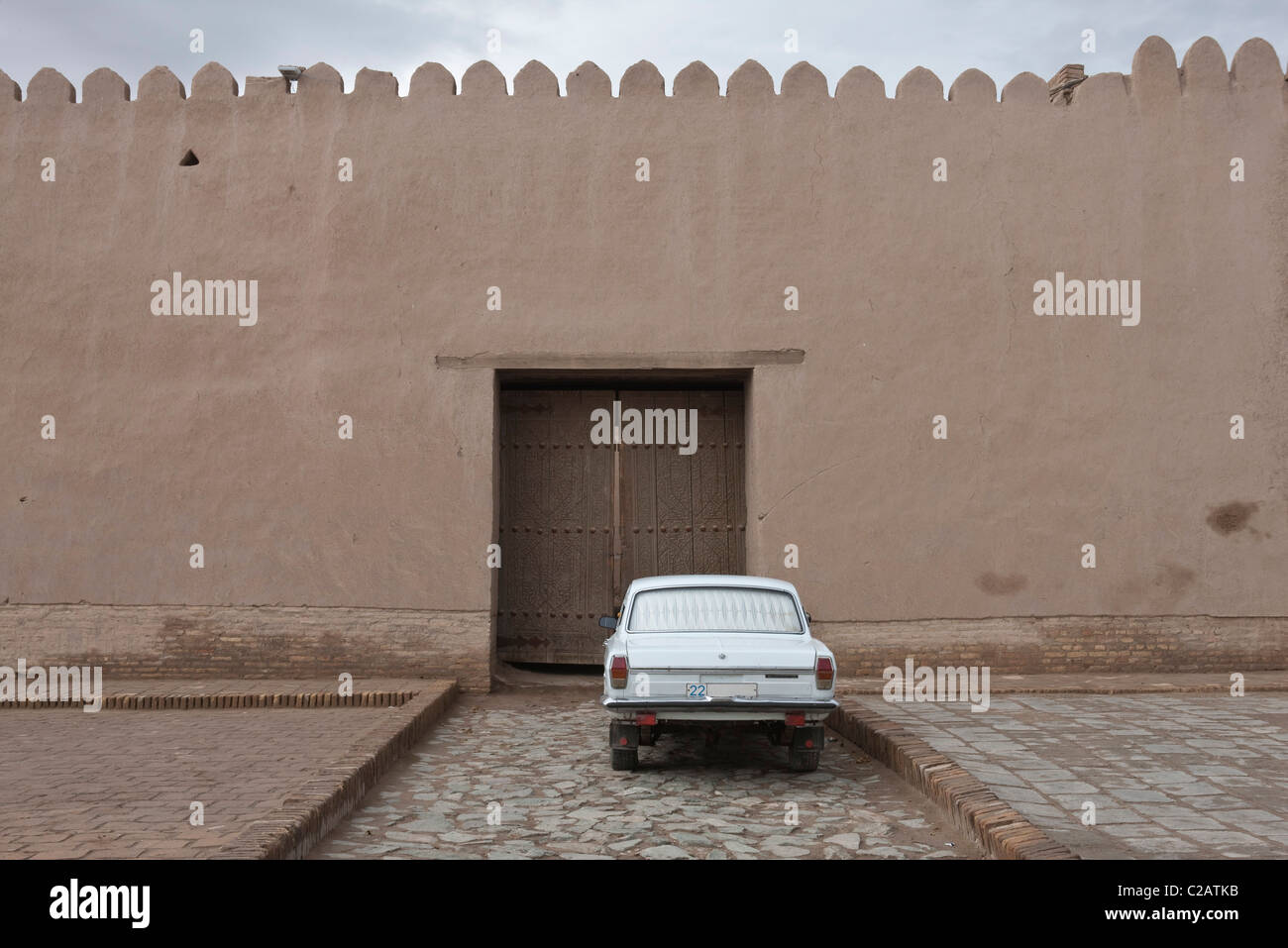 Uzbekistan, Khiva, Itchan Kala, auto parcheggiata di fronte vecchie mura della città Foto Stock