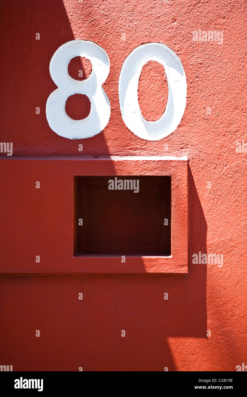 Il numero civico e la cassetta postale sulla parete rossa Foto Stock