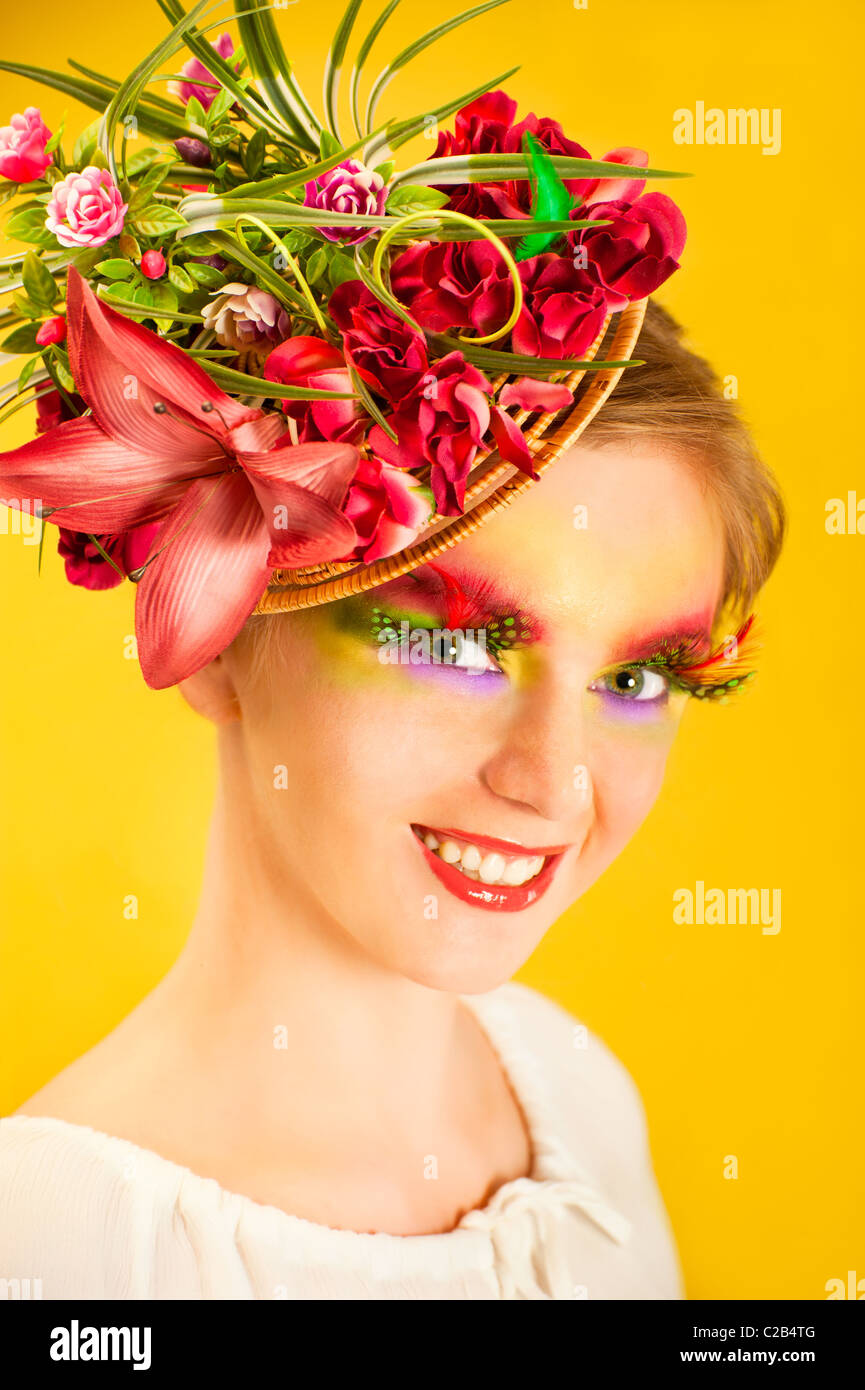 Bella giovane donna con fiore creative cap. Trucco Artistico con una lunga piuma ciglia artificiali Foto Stock