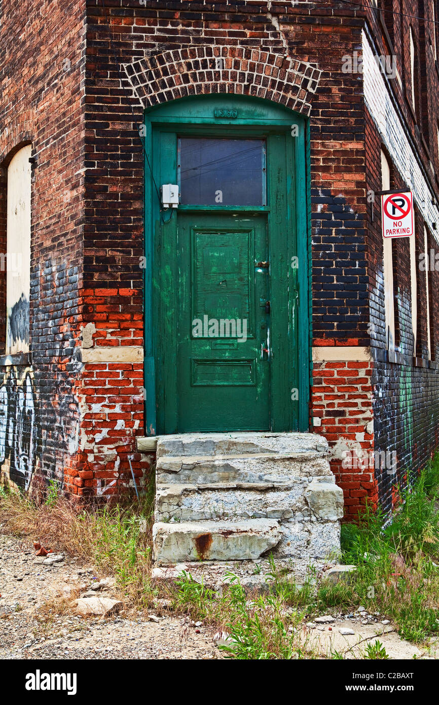 Ingresso alla costruzione abbandonata con la porta verde, stacca la vernice e sbriciolamento scale. Foto Stock
