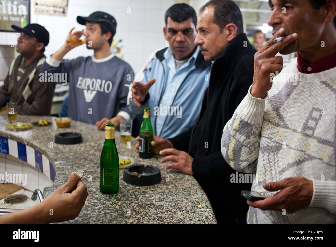 Gli uomini di bere alcol (Celtia birra e whisky) al banco bar a Sfax, Tunisia. Foto Stock