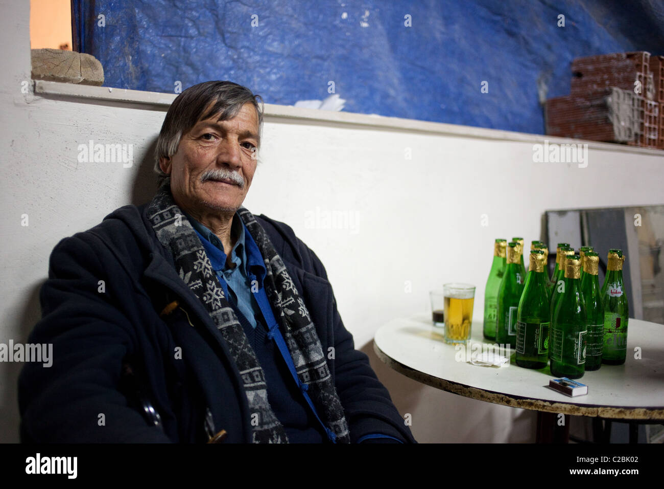Un ritratto di un uomo con Celtia bottiglie di birra in una tavola in un bar a Sousse, Tunisia. Foto Stock