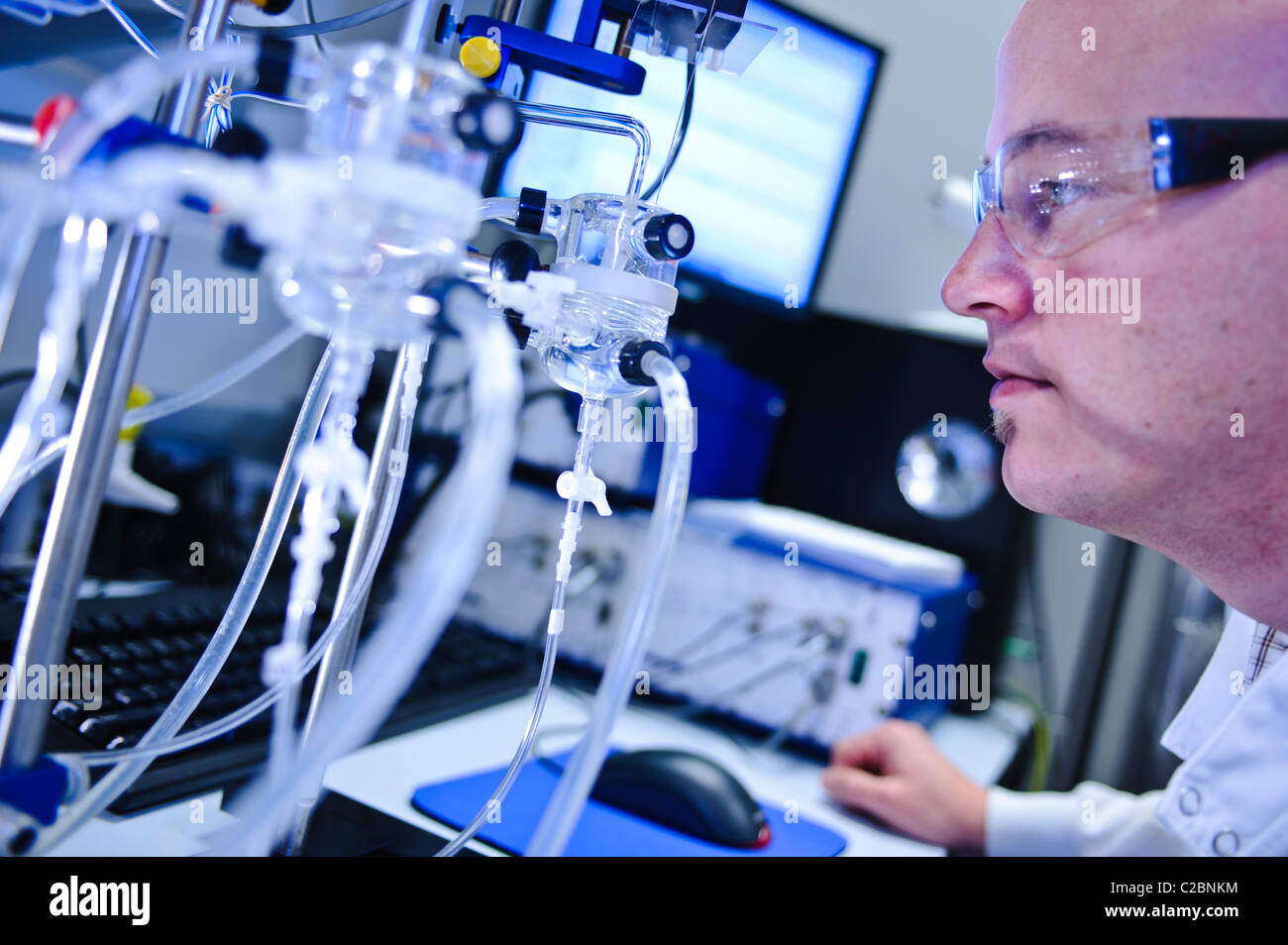 Scienziato maschio degli occhiali guardando alla apparecchiatura in laboratorio di scienze Foto Stock