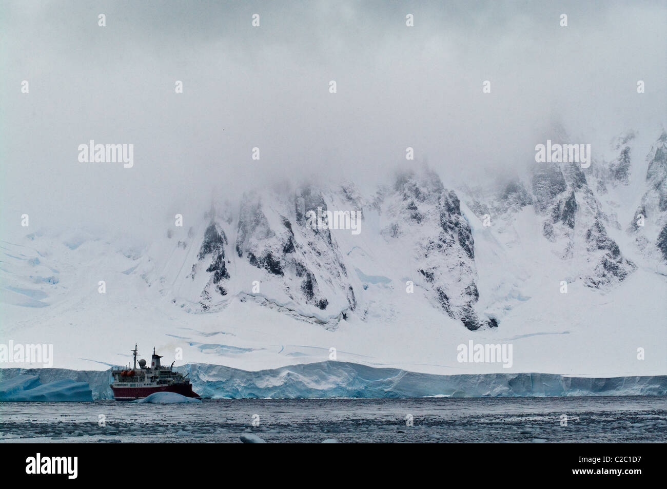 Vasto e minacciose montagne dwarf un ghiacciaio e nave di ecoturismo. Foto Stock