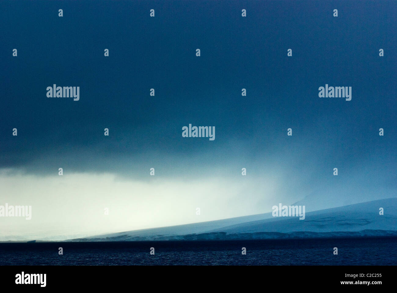 Una minacciosa tempesta scende oltre un imponente ghiacciaio in esecuzione nel mare. Foto Stock