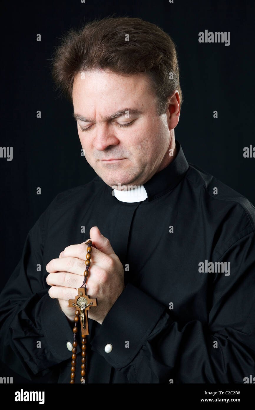 Sacerdote cattolico di pregare con il suo rosario. Foto Stock