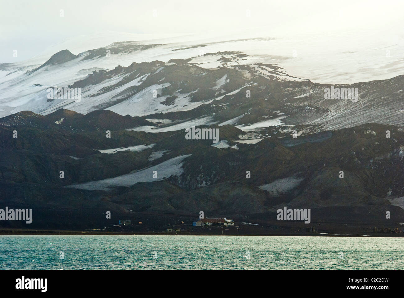 Le rovine di una stazione baleniera nelle ombre di un robusto icy mountain. Foto Stock