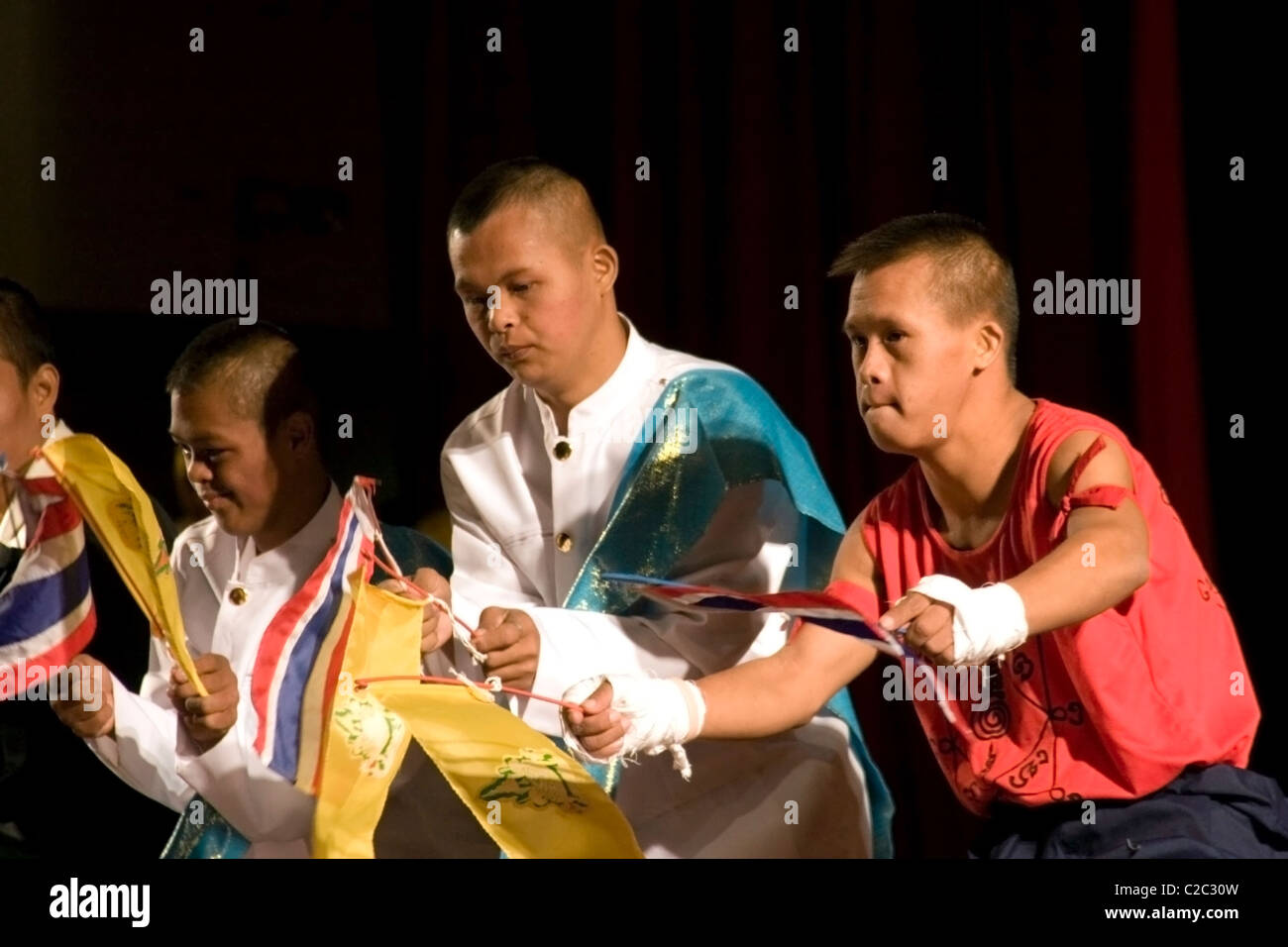 Un gruppo di giovani disabili uomini stanno eseguendo con bandiere del Lao cultura nazionale Hall di Vientiane, Laos. Foto Stock